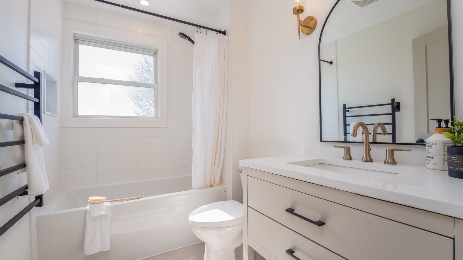 Bright renovated bathroom with tub, vanity and black hardware