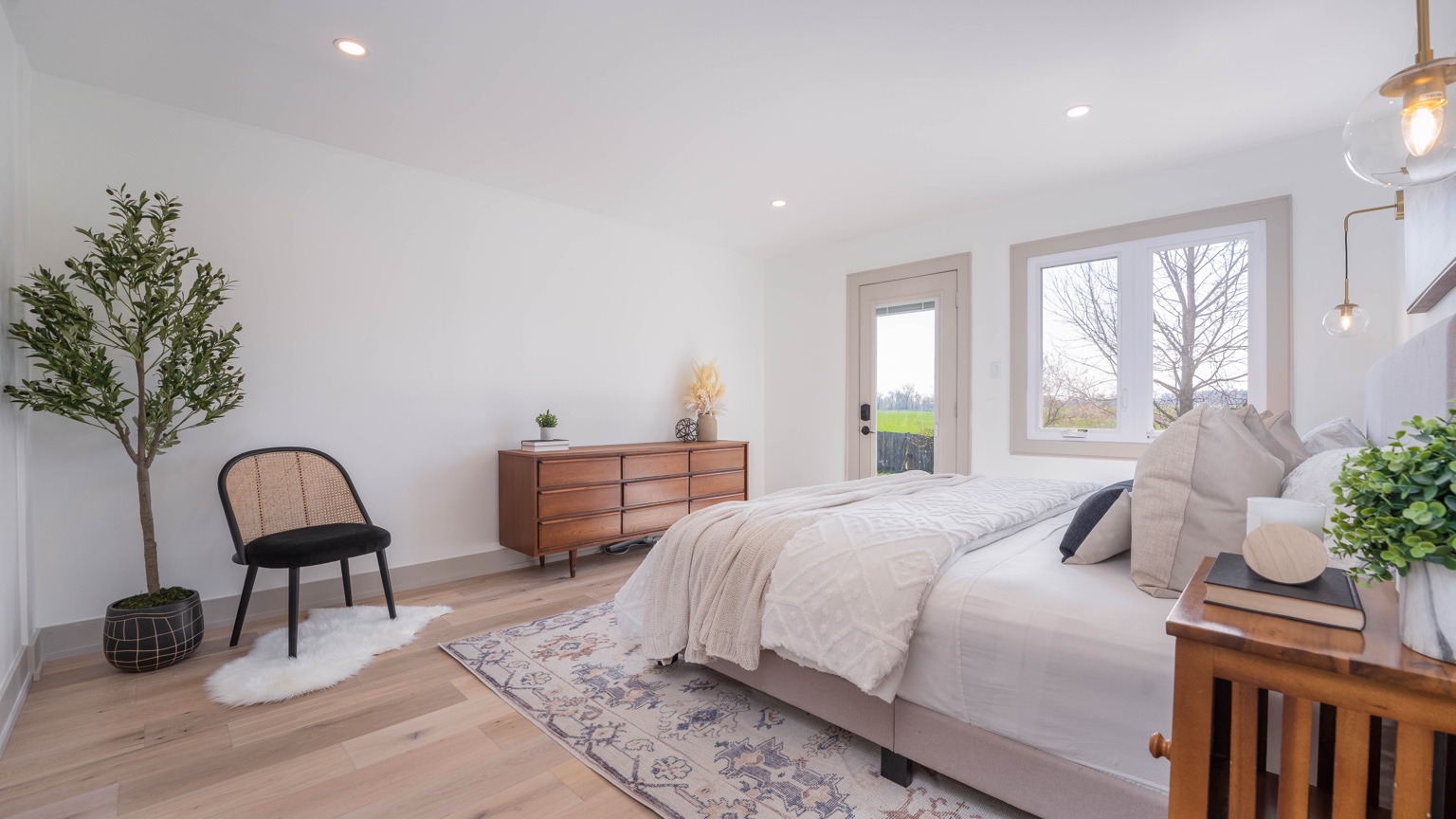 Bright finished bedroom with large window and light wood floors