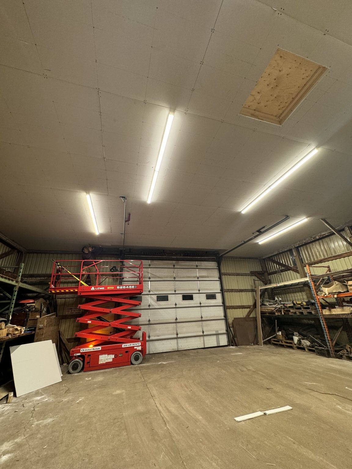 Ceiling work being completed from a scissor lift inside a large shop space