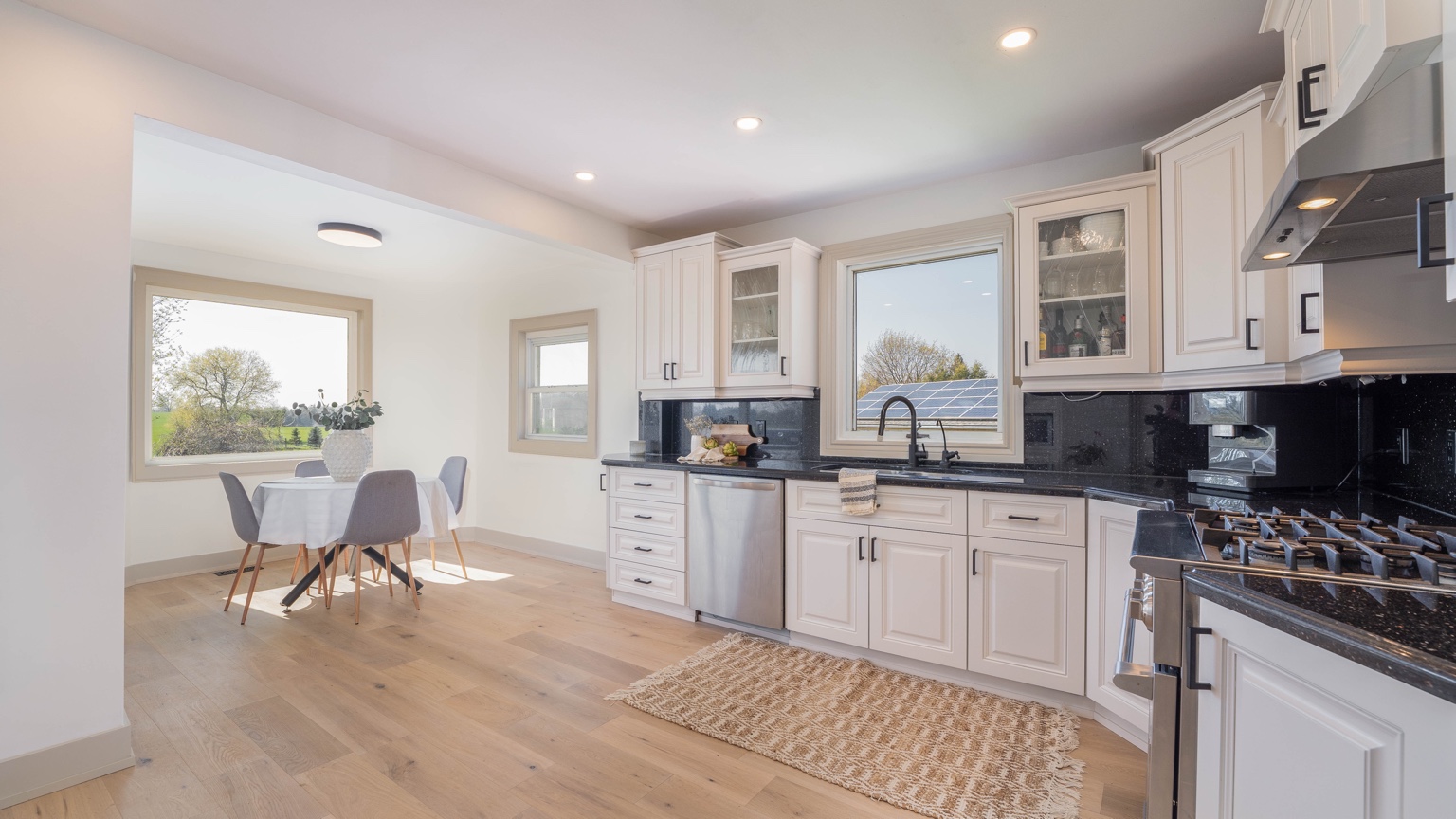 Bright renovated kitchen with white cabinetry, black counters and large window
