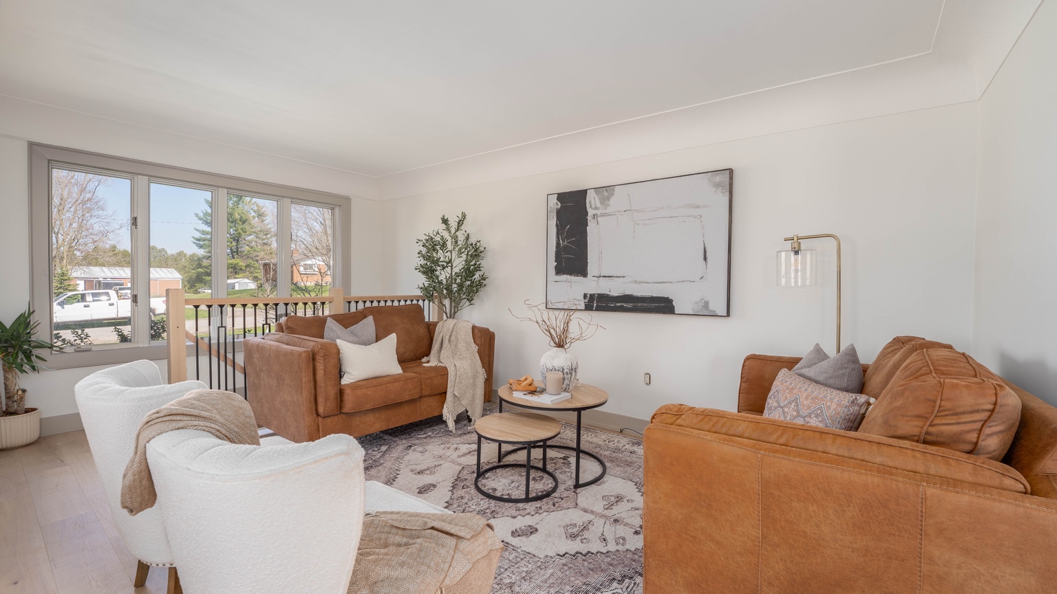 Finished living room with large windows and warm neutral furnishings